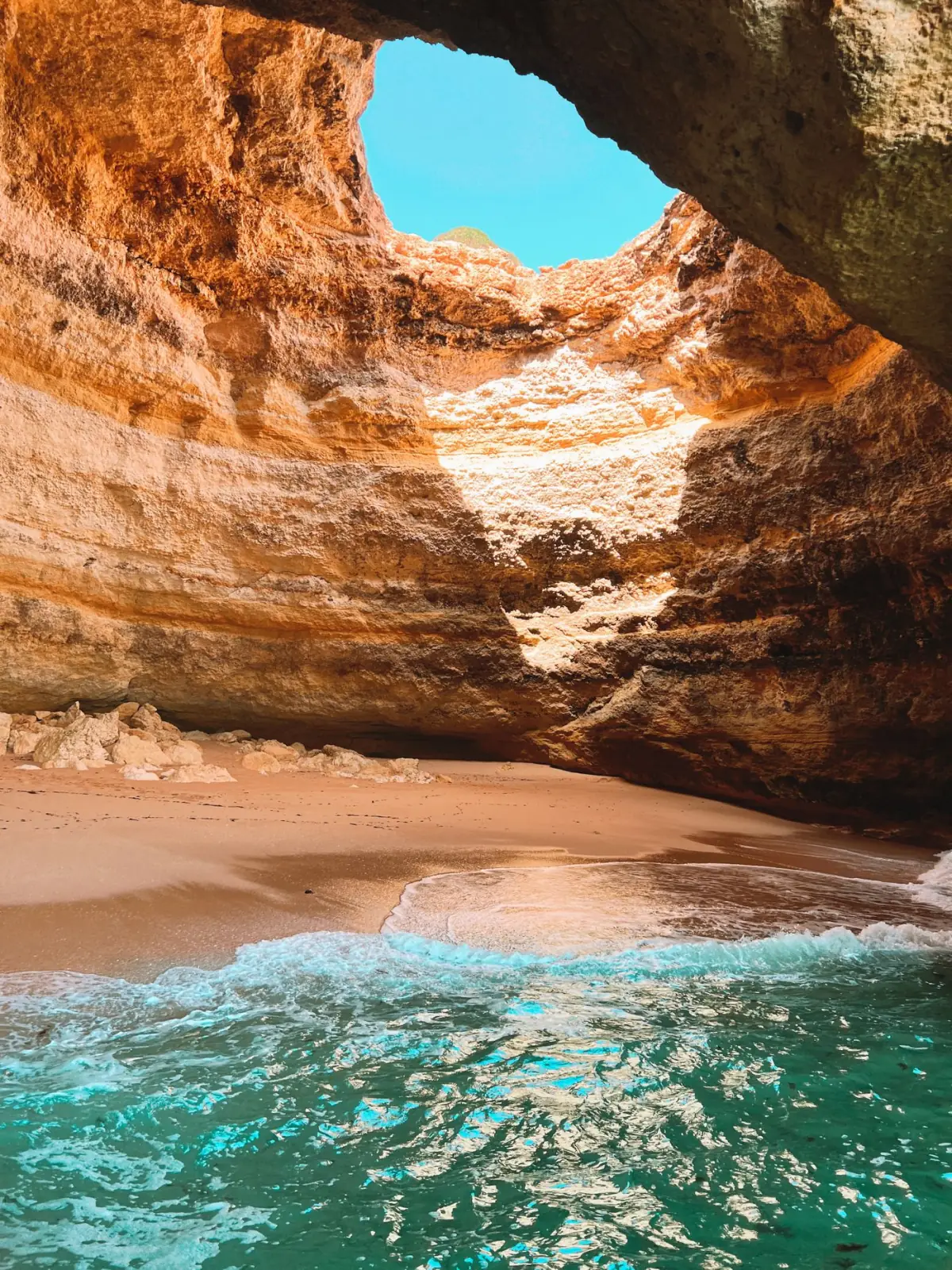 Interior de gruta marinha iluminada com águas turquesa no litoral de Lagoa, Algarve