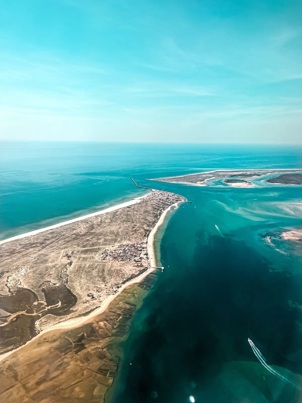 Vista aérea de uma praia do Algarve de areal largo com águas turquesa e calmas
