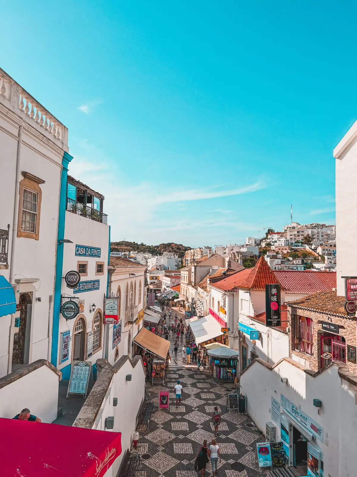 Rua mediterrânica colorida na Cidade Velha de Albufeira com fachadas brancas e azulejos