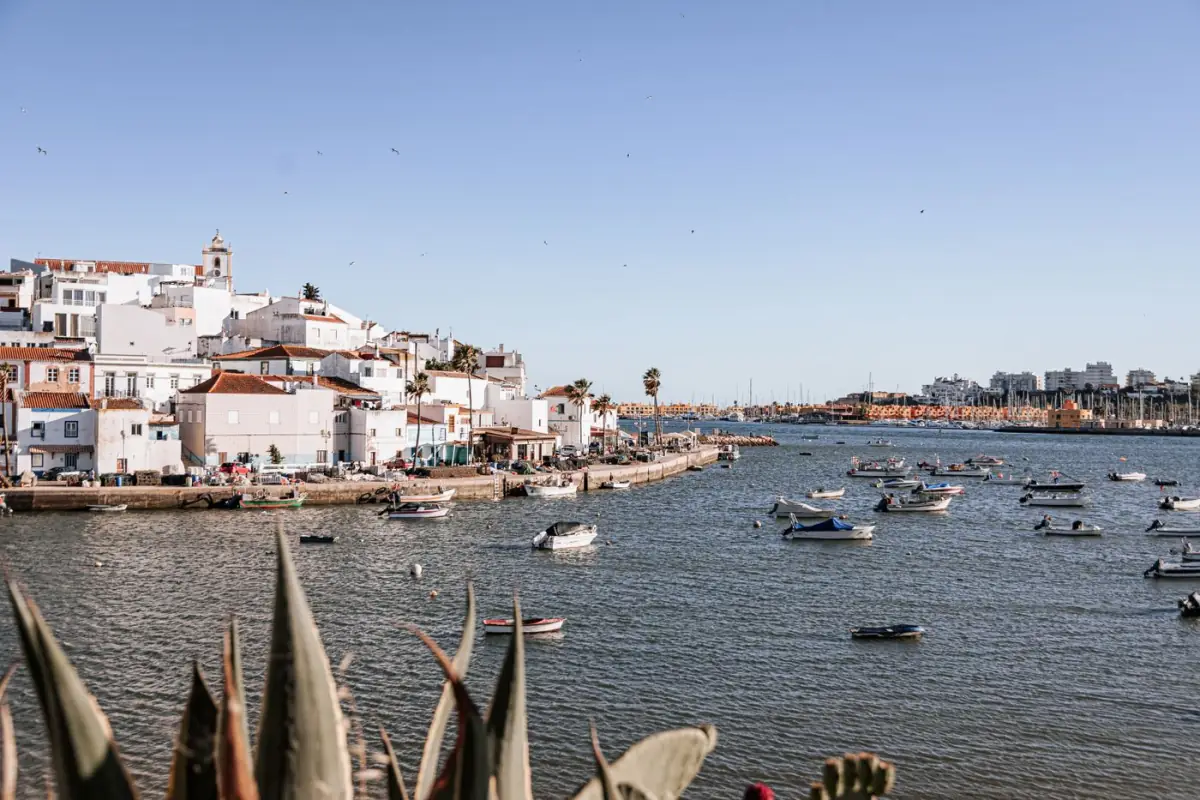 Barcos de pesca coloridos junto a casas brancas numa vila piscatória do Barlavento algarvio