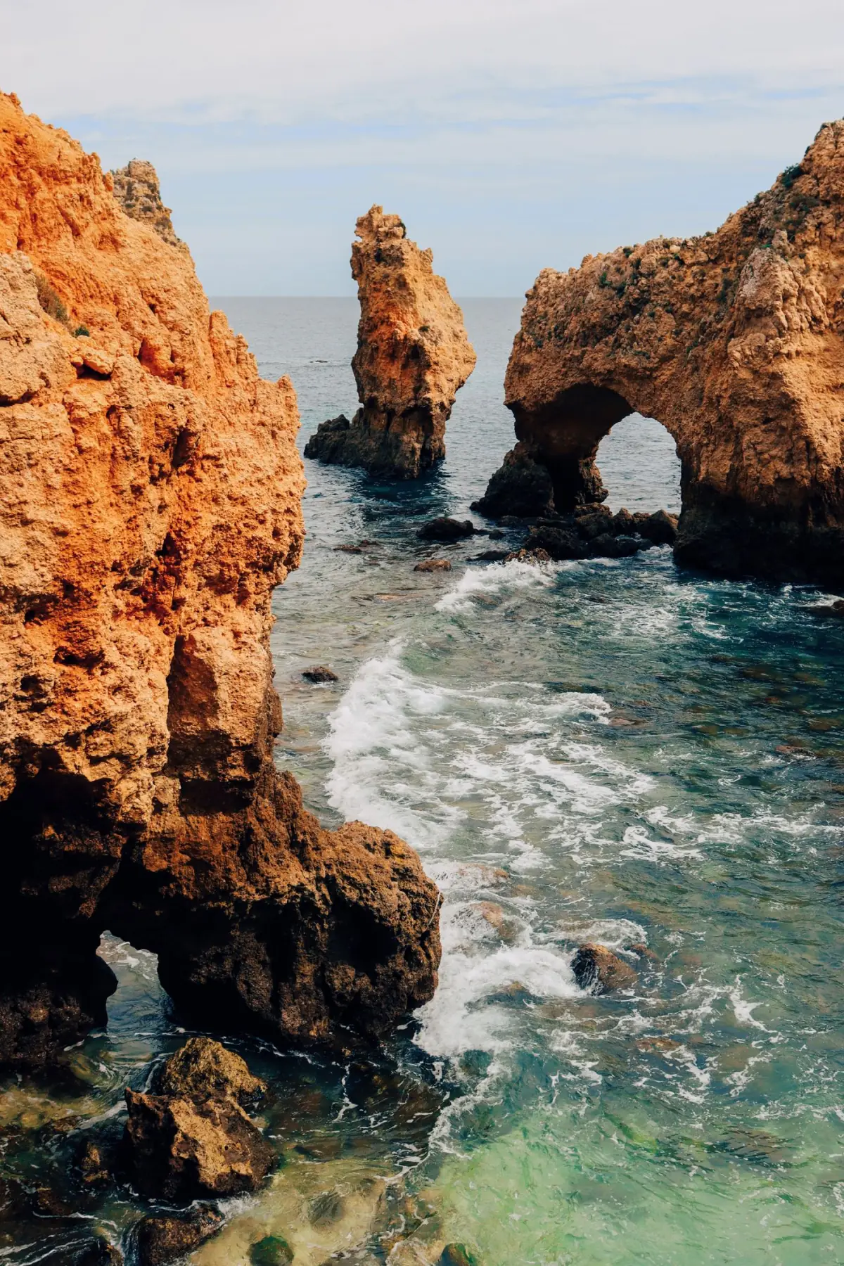 Formações rochosas com arcos naturais e água clara turquesa numa enseada de Lagos