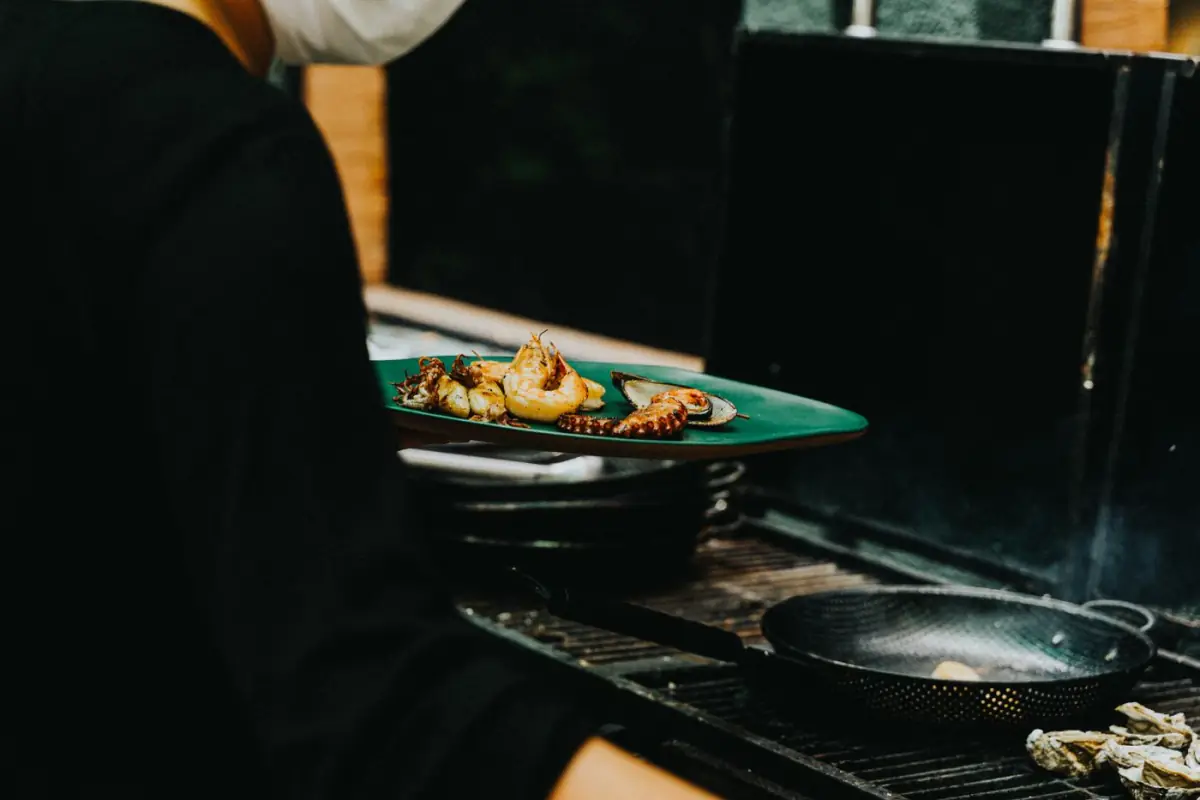 Cozinheiro a preparar polvo e mexilhões na cozinha de um restaurante de peixe em Santa Luzia
