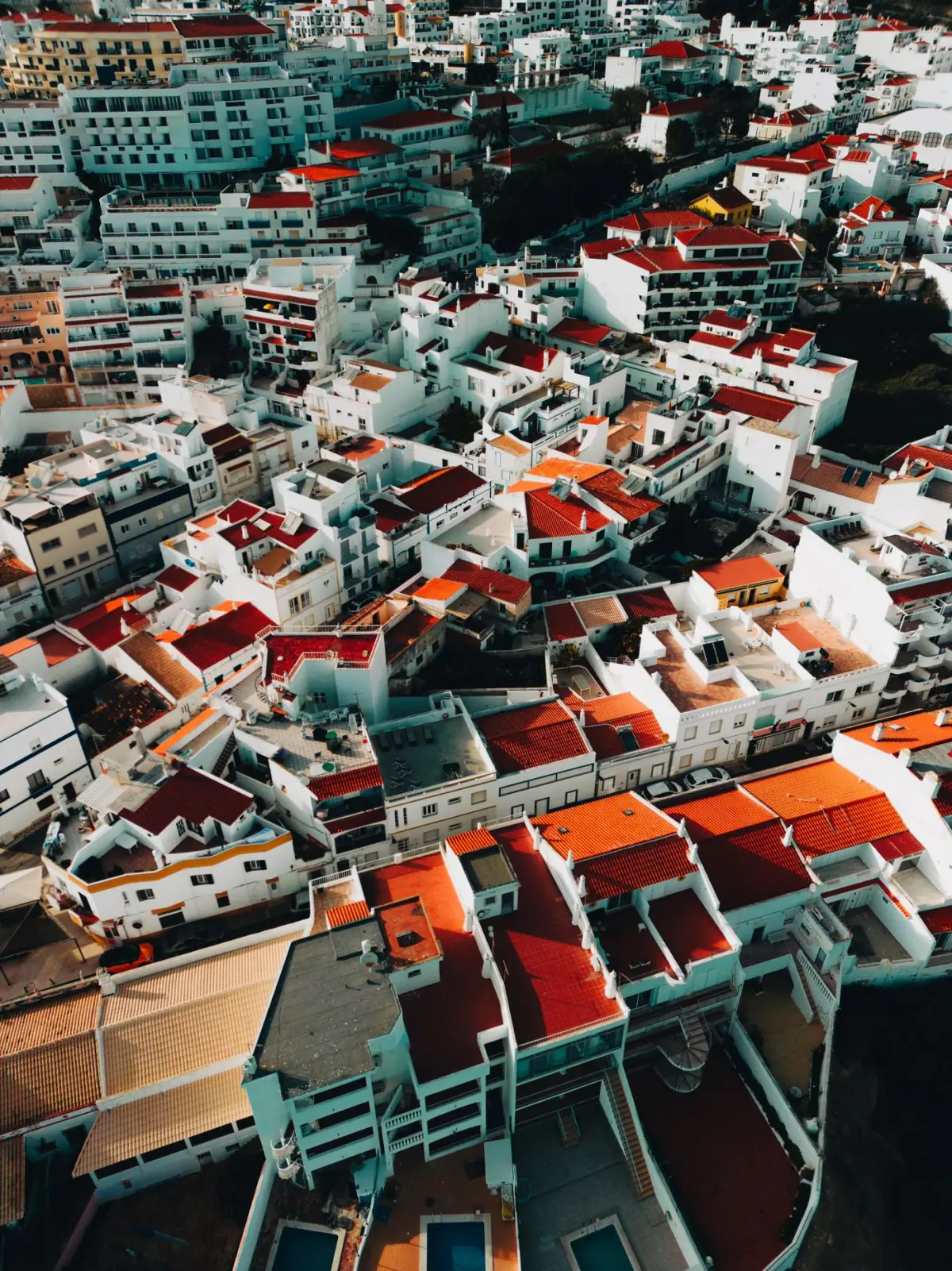 Vista aérea de telhados vermelhos de uma vila do Algarve junto ao mar azul