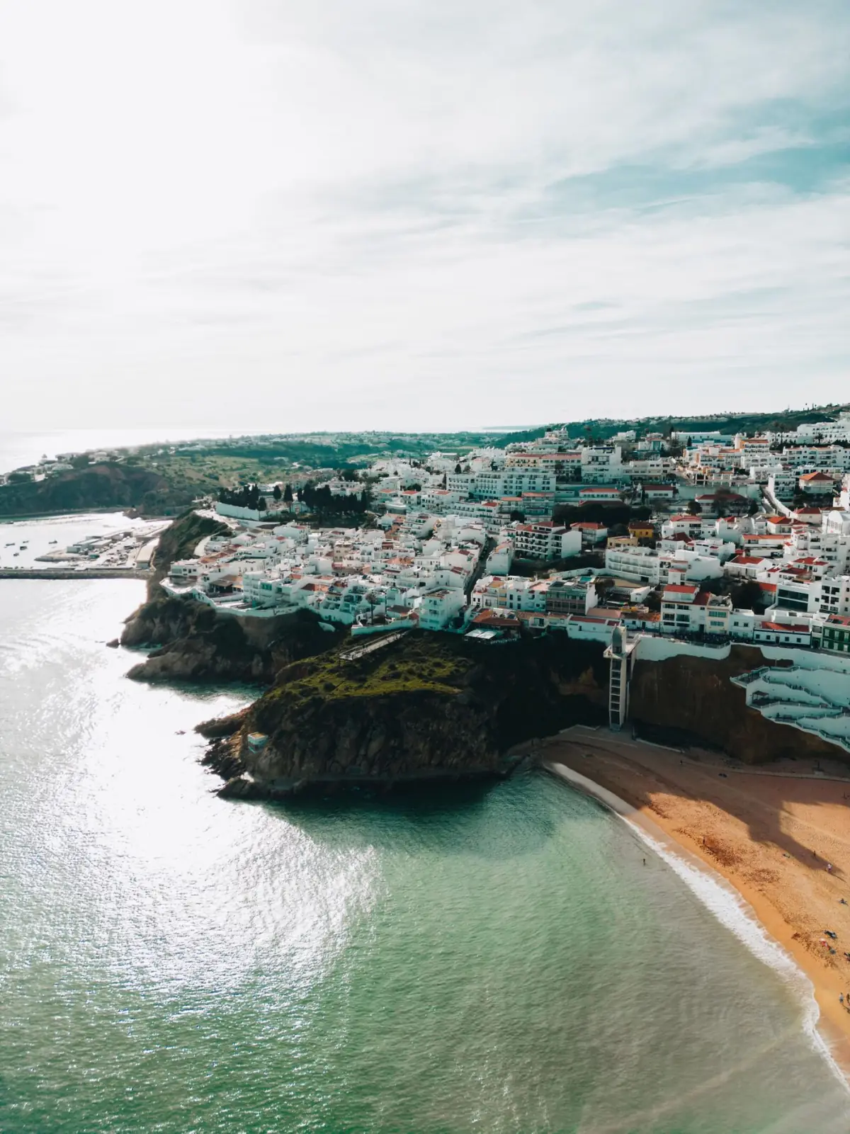 Vista aérea de uma vila do Algarve com falésias e praias acessíveis por estrada
