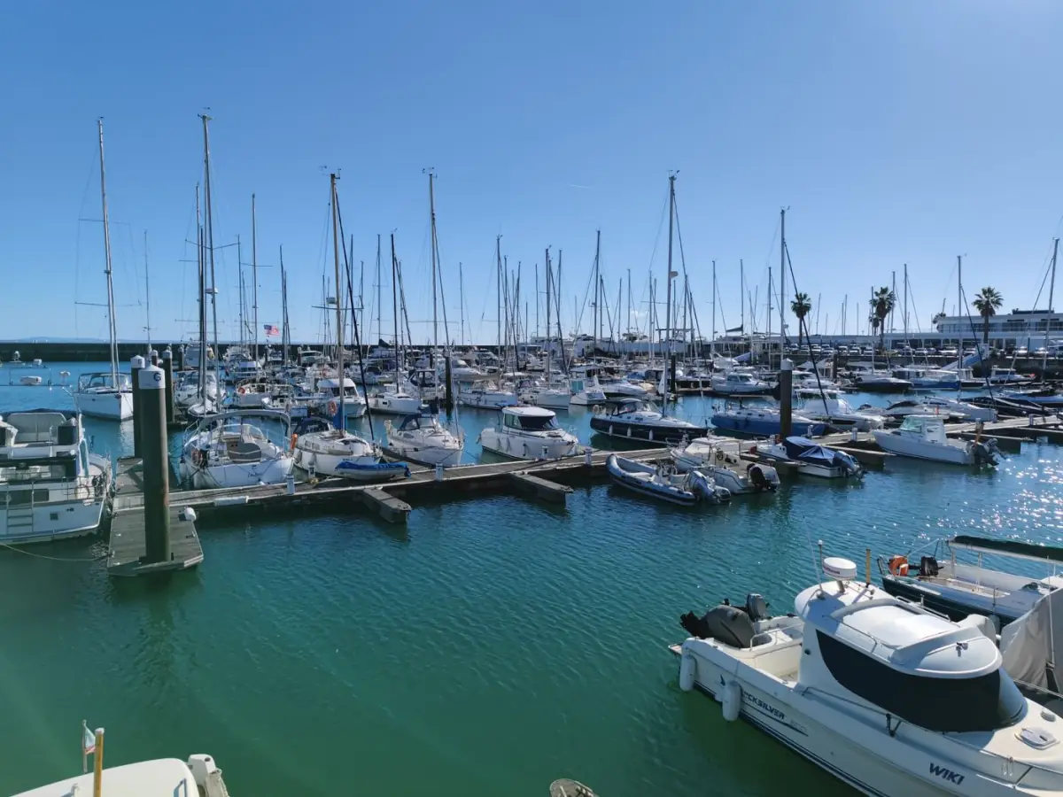 Marina de Vilamoura repleta de barcos e iates em águas calmas, com edifícios brancos em redor