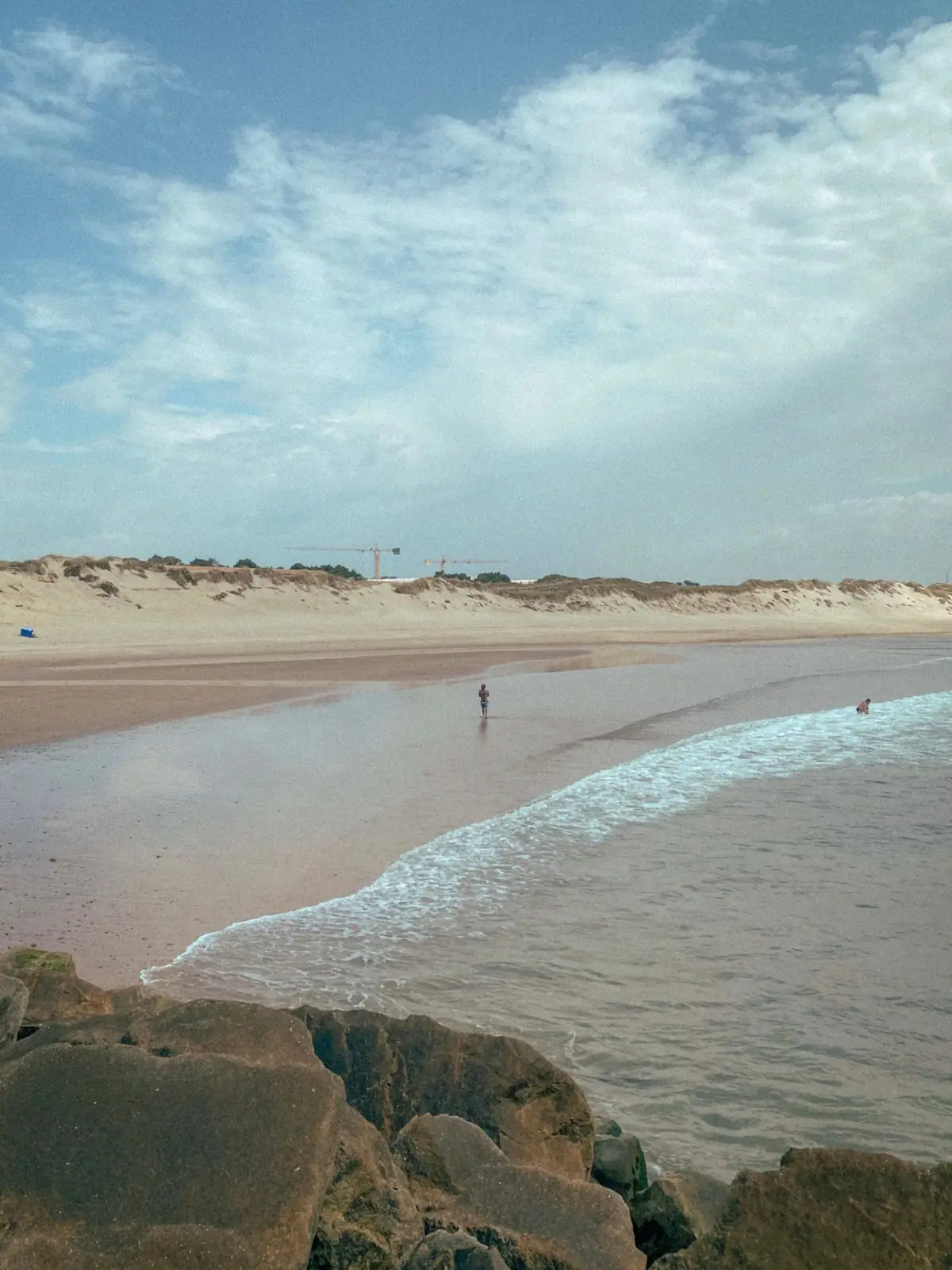 Praia serena do Algarve com um único caminhante junto ao mar fora de época
