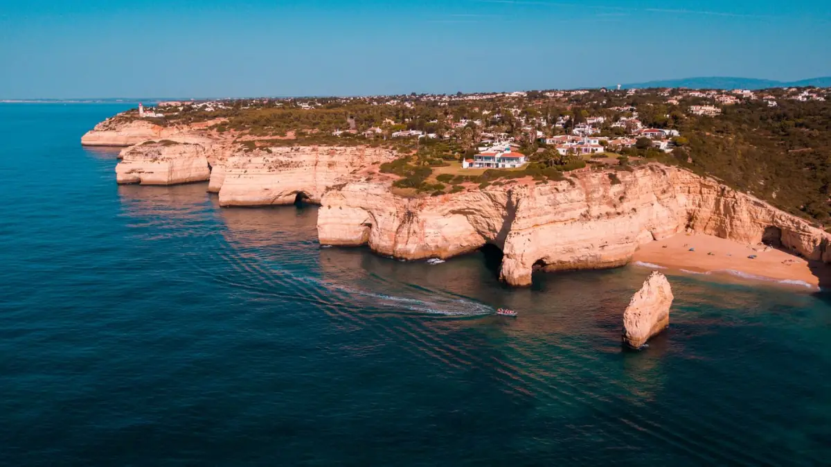 Casas brancas algarvias junto ao mar sobre uma falésia, com o oceano azul ao fundo