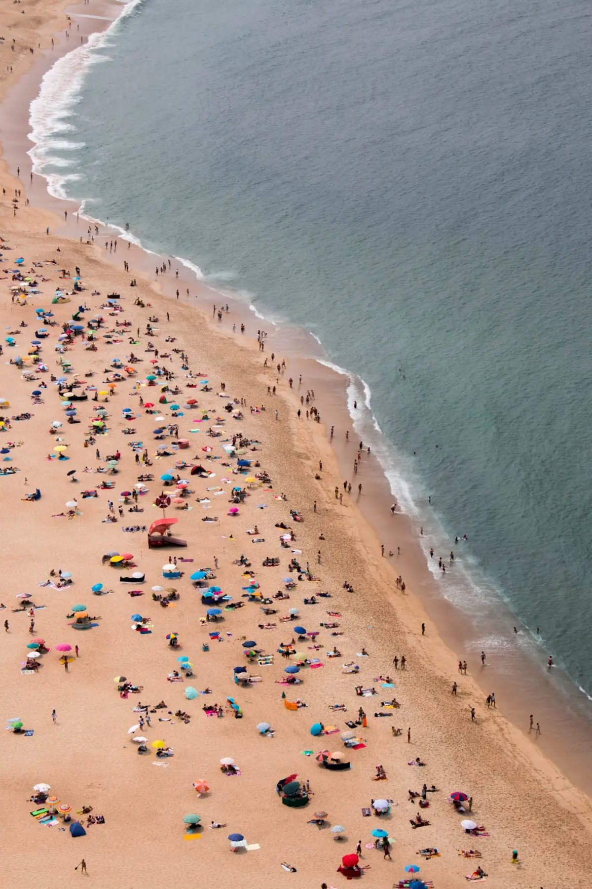 Vista aérea de praia apinhada de guarda-sóis num dia de verão no Algarve