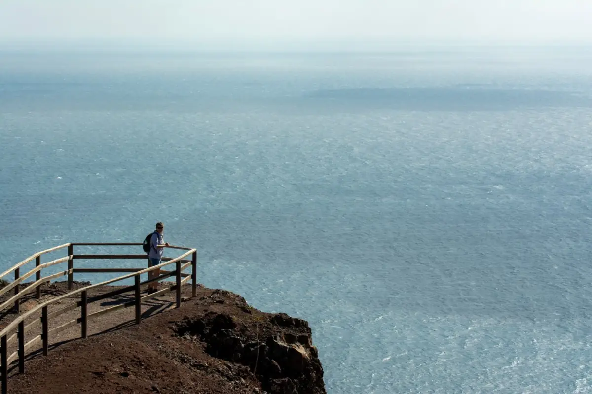 Viajante de costas num miradouro sobre o vasto oceano Atlântico no Algarve
