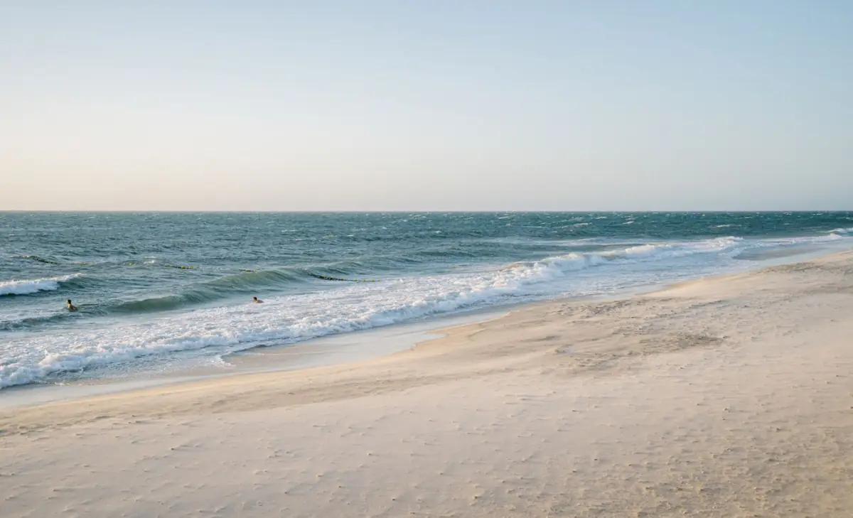 Praia pública tranquila do Algarve com ondas suaves e acesso livre