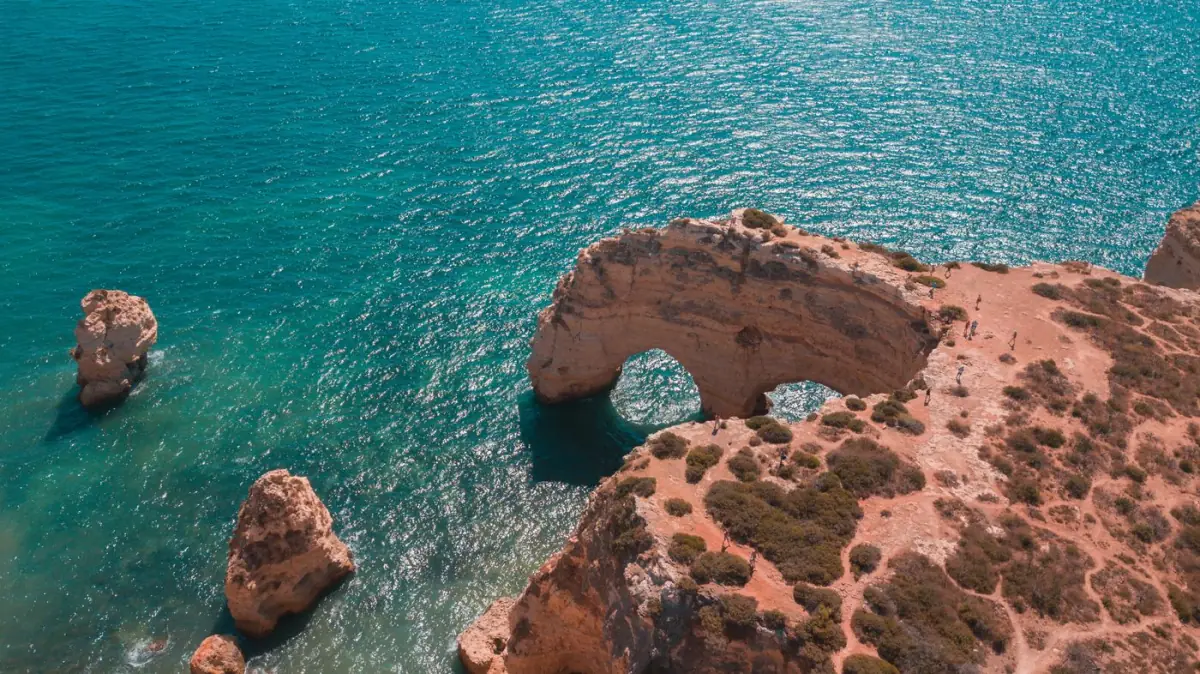 Arco natural da Praia da Marinha visto do ar sobre o mar azul
