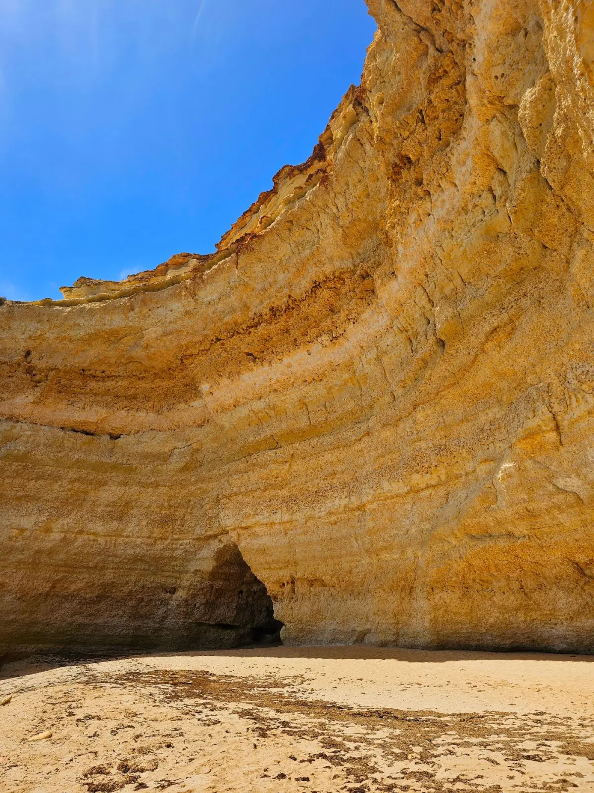 Falésias calcárias douradas e entrada de gruta marinha junto a Carvoeiro, no Algarve