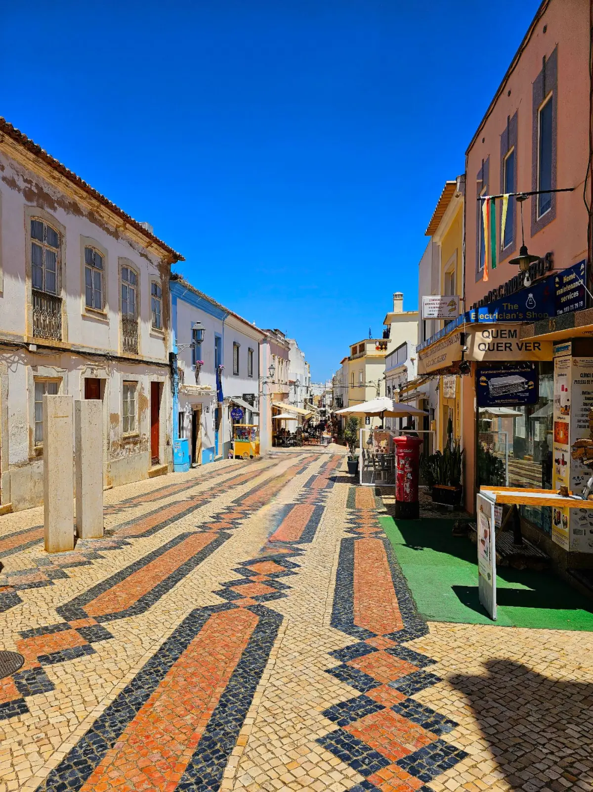 Rua de calçada portuguesa colorida no centro histórico de Lagos, com fachadas tradicionais e esplanadas