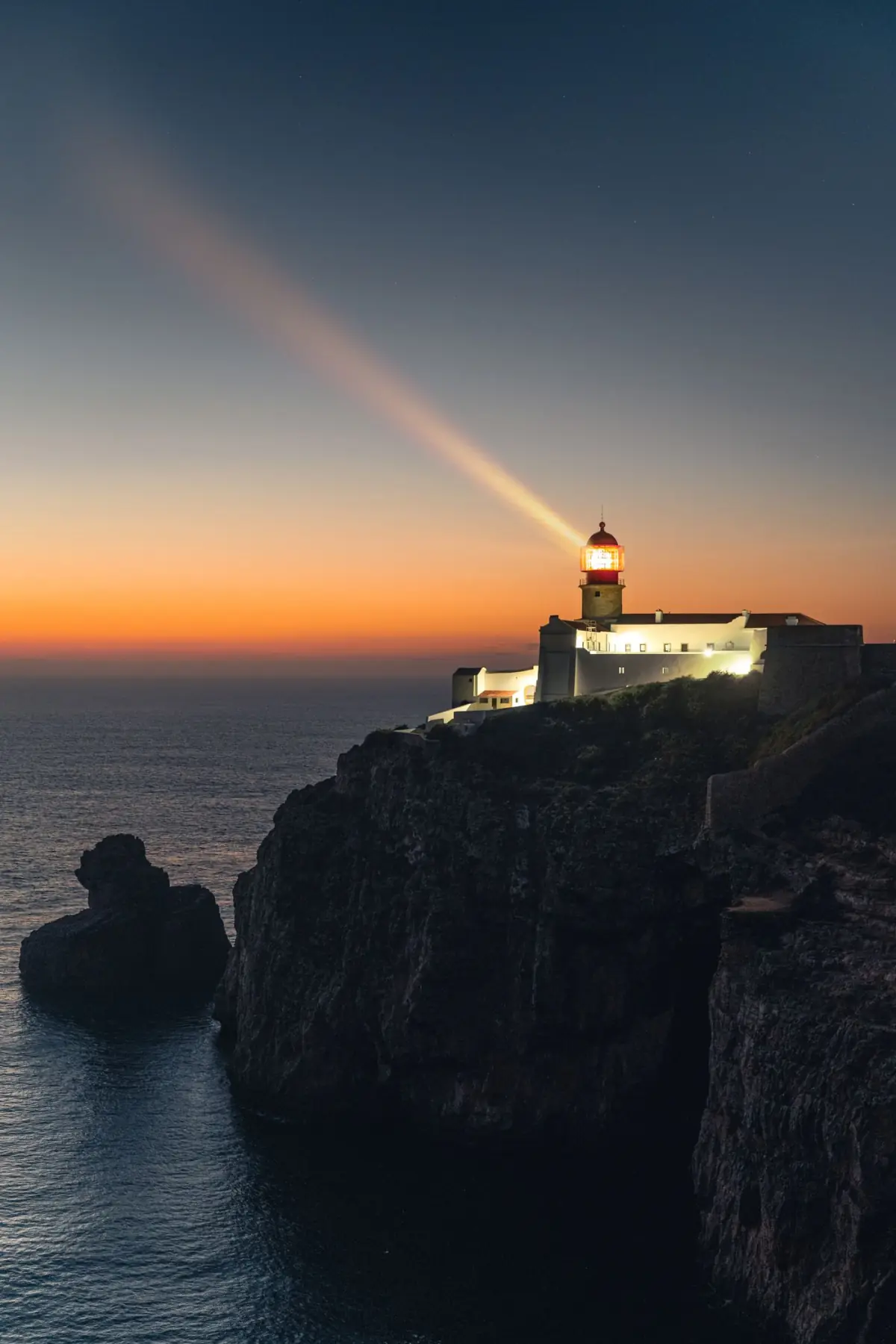 Farol do cabo de São Vicente ao pôr do sol, sobre falésia recortada