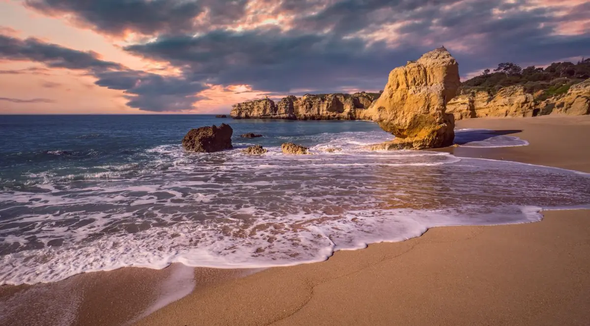 Praia dourada e falésias do Algarve com céu cor de fogo ao pôr do sol
