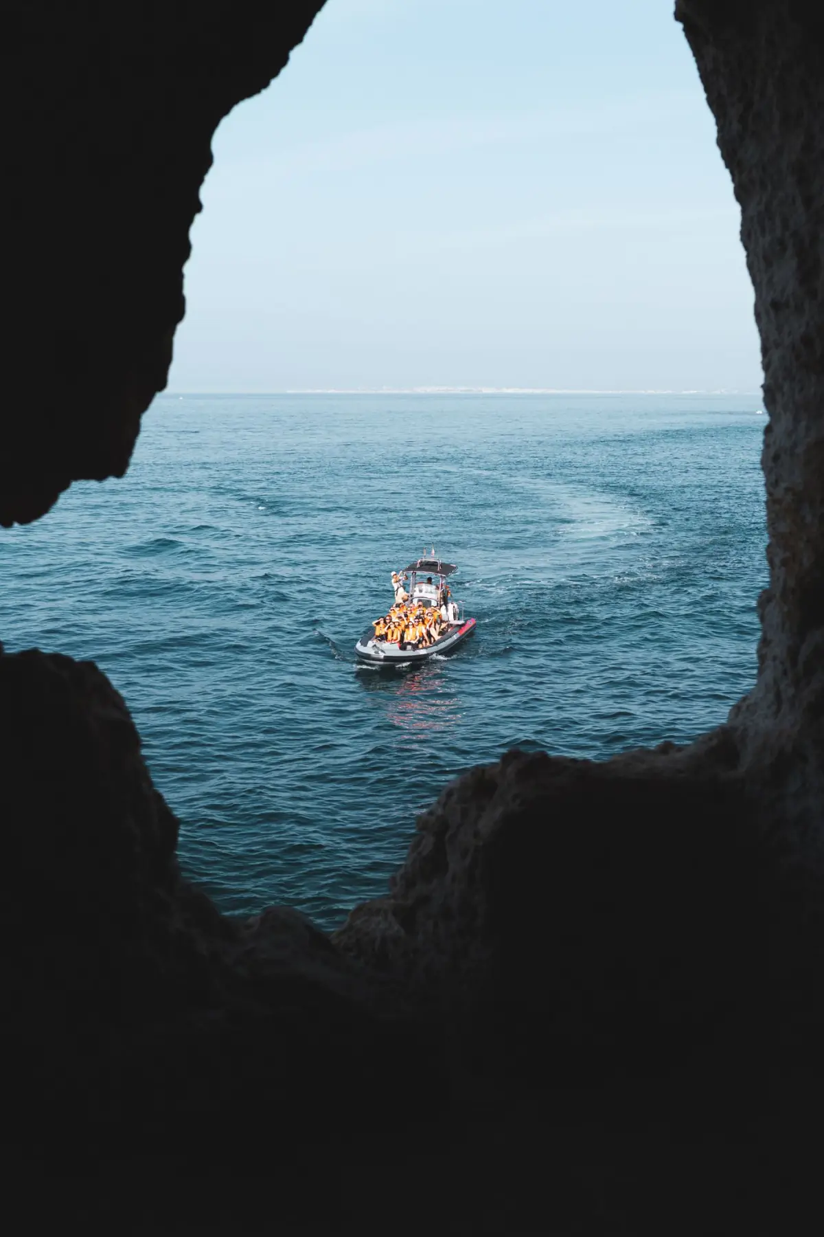Pequeno barco a navegar visto do interior de uma gruta na costa de Carvoeiro