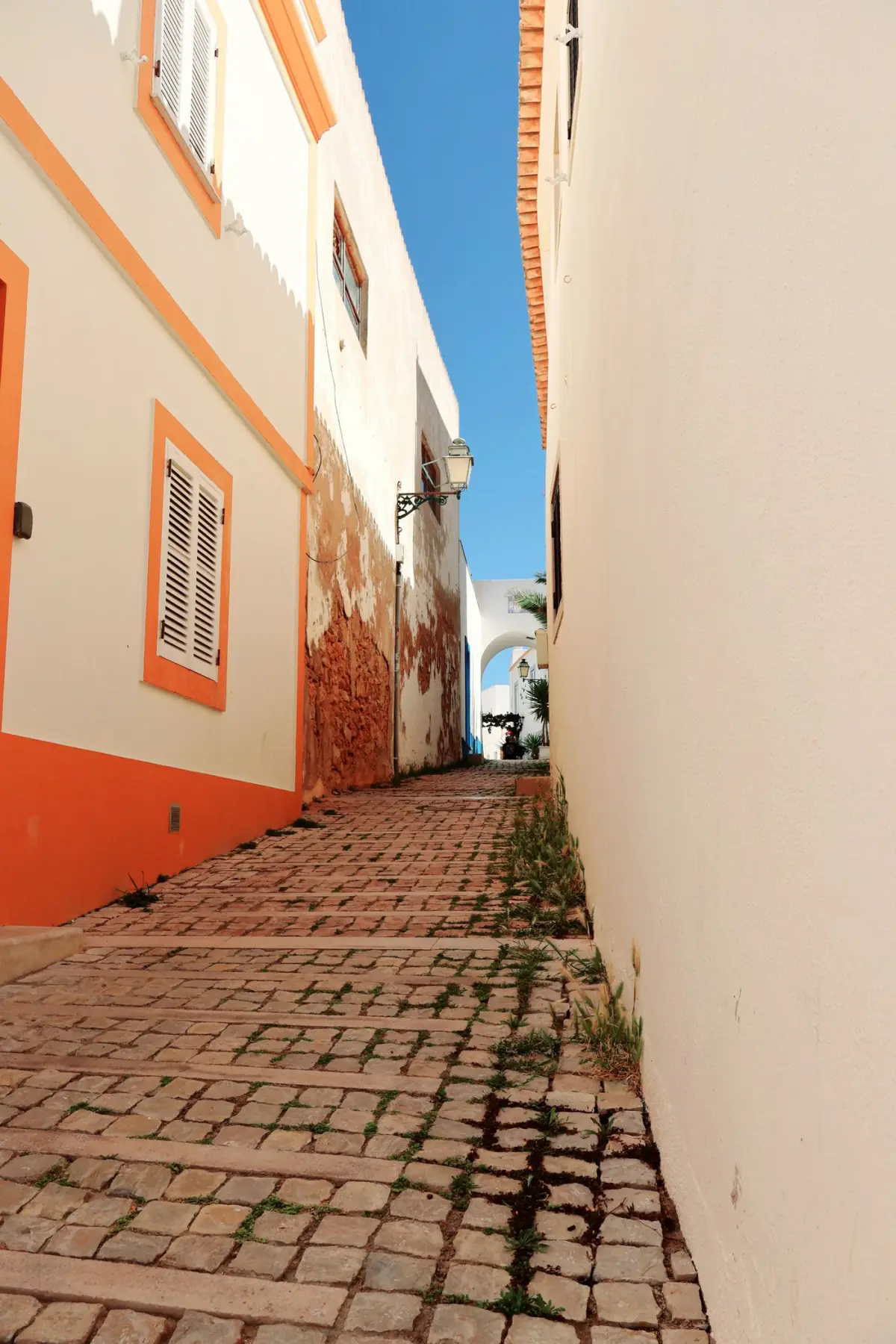 Ruela de calçada portuguesa entre casas coloridas no centro histórico de Tavira, no Sotavento do Algarve