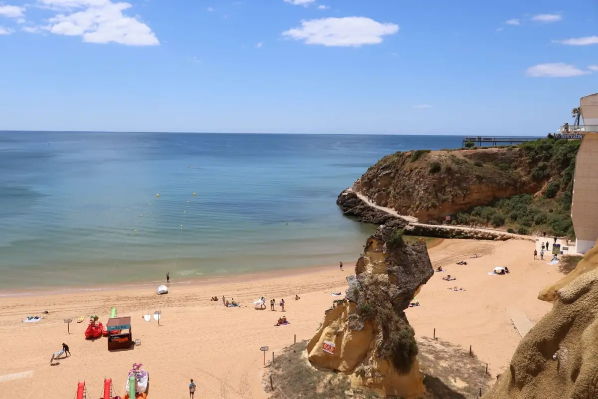 Areal largo da Praia da Rocha com falésias douradas e mar calmo
