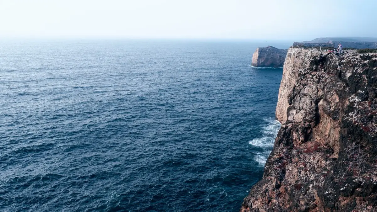 Falésias escarpadas a encontrar o oceano Atlântico junto a Sagres ao fim da tarde