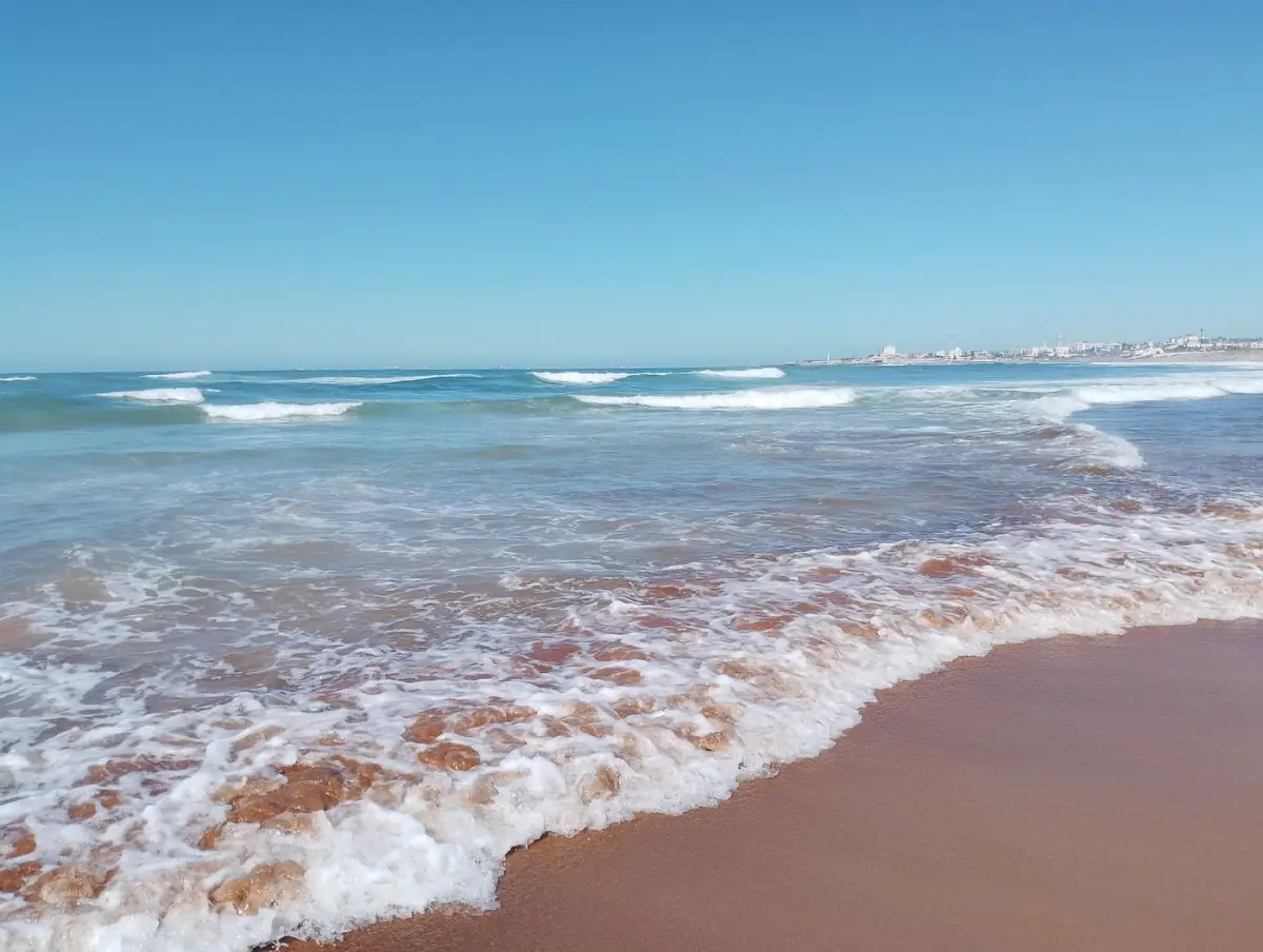 Areal sereno de Armação de Pêra com ondas suaves a quebrar num dia de sol