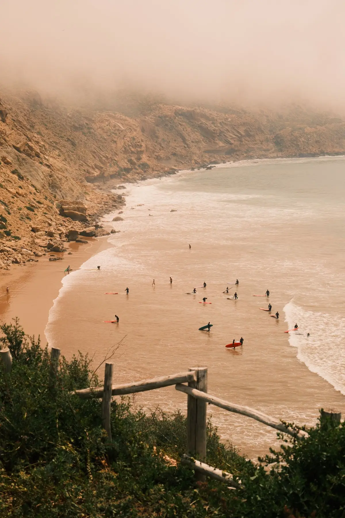 Surfistas numa praia da Costa Vicentina com bruma matinal sobre o mar
