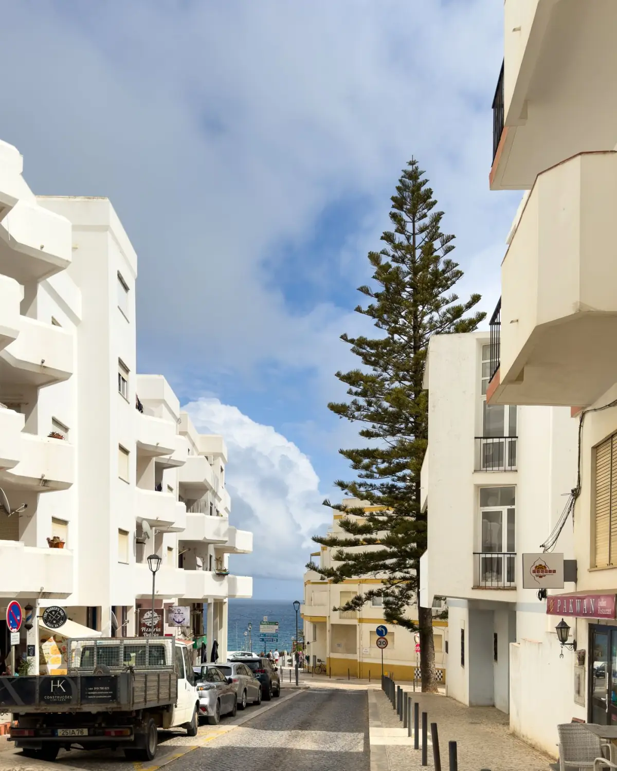 Rua da Praia da Luz a descer para o mar, com ciprestes e vista para o Atlântico
