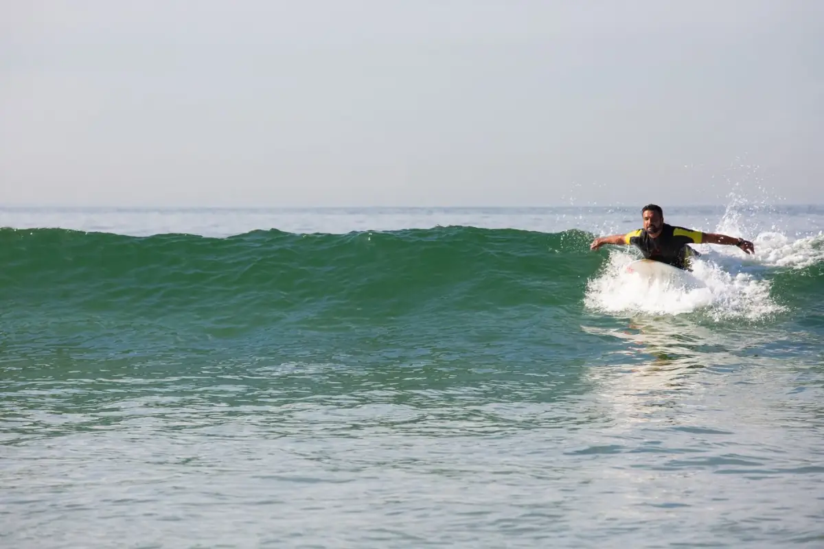 Surfista de fato a contornar uma onda espumosa num dia de ondulação na costa oeste do Algarve