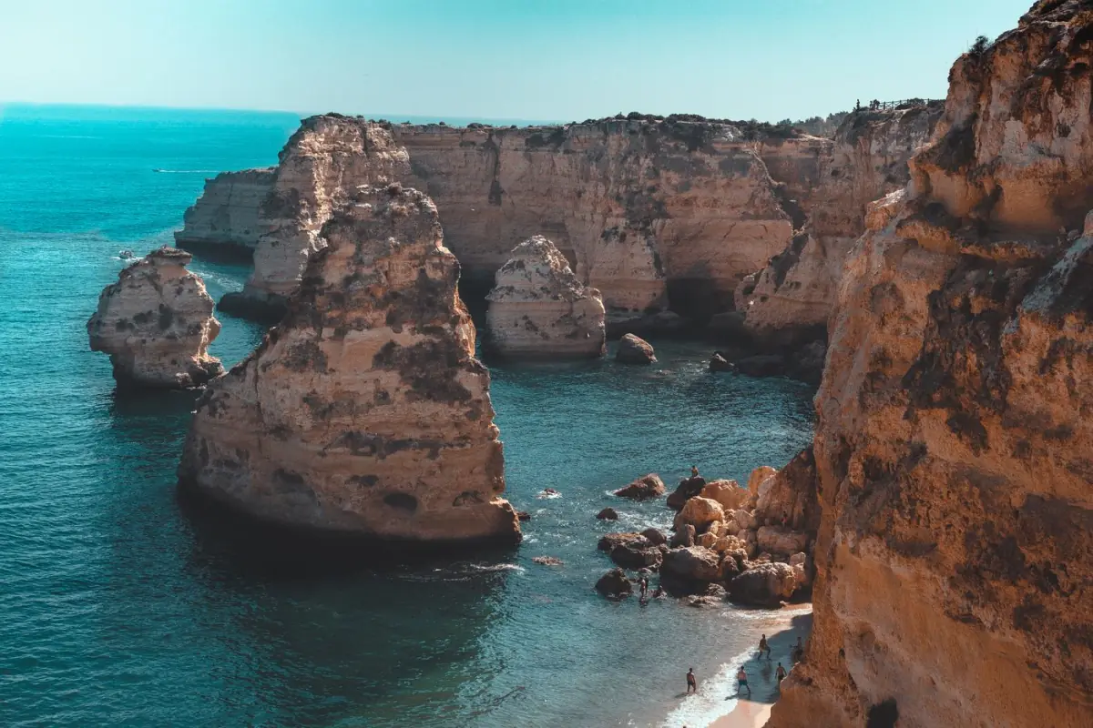 Formações rochosas e águas azul-esverdeadas na Praia da Marinha, em Lagoa