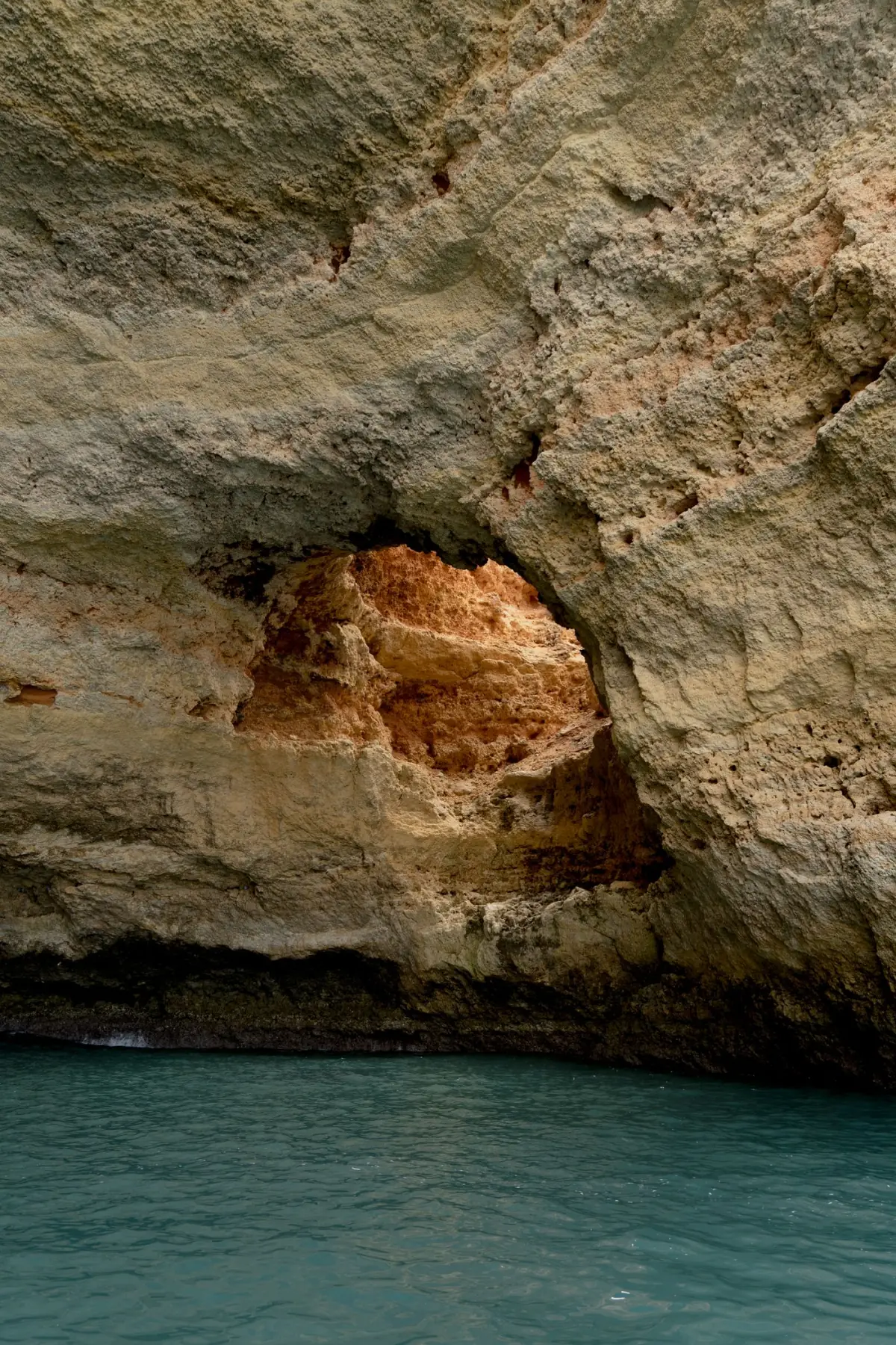 Gruta de calcário aberta para o mar no litoral do Algarve, com luz a entrar pela abertura