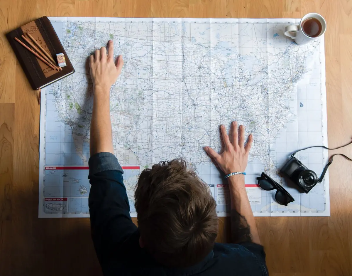 Mapa do Algarve sobre uma mesa com máquina fotográfica e café, durante o planeamento da viagem
