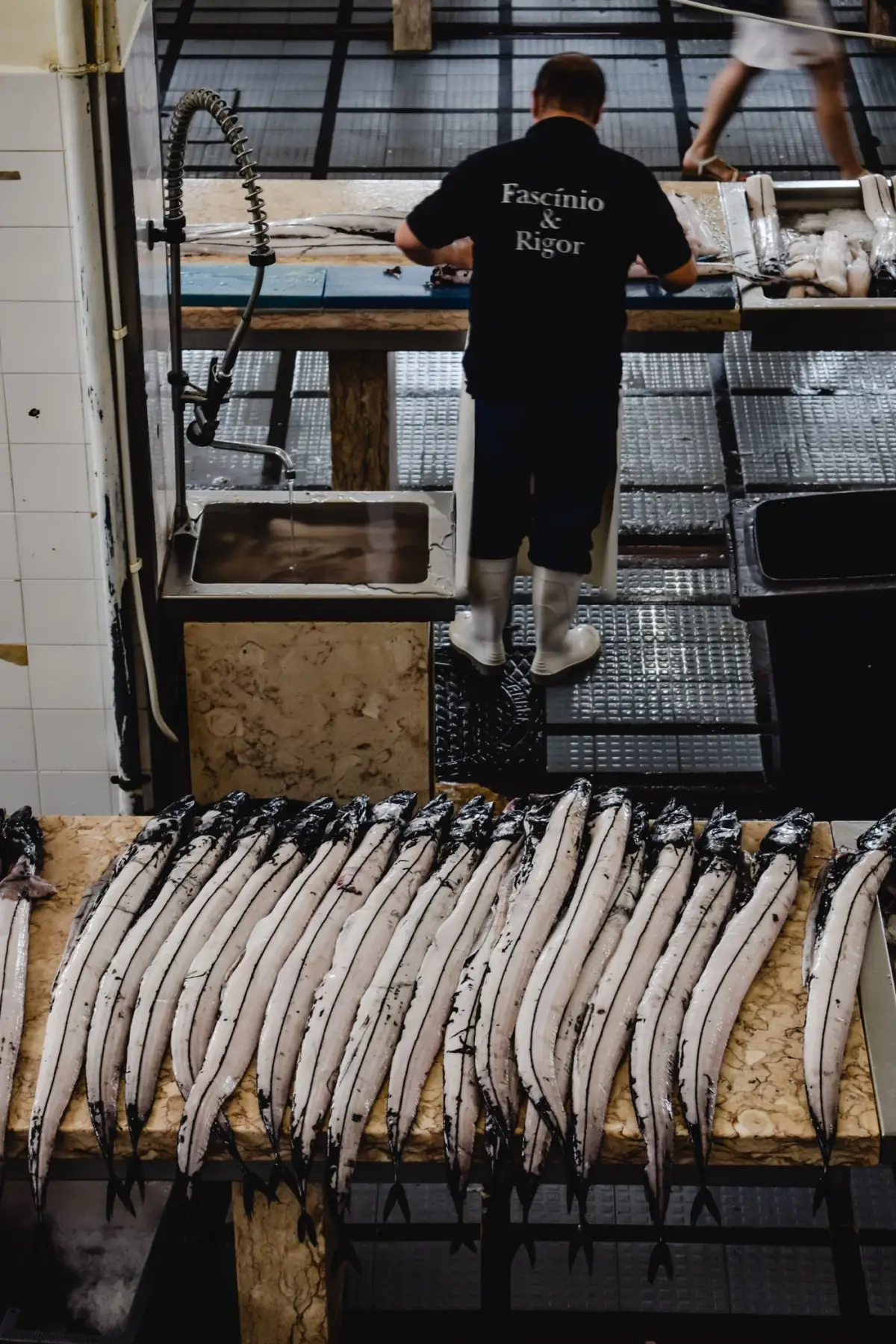 Peixeiro a preparar peixe fresco numa banca de mercado no Algarve