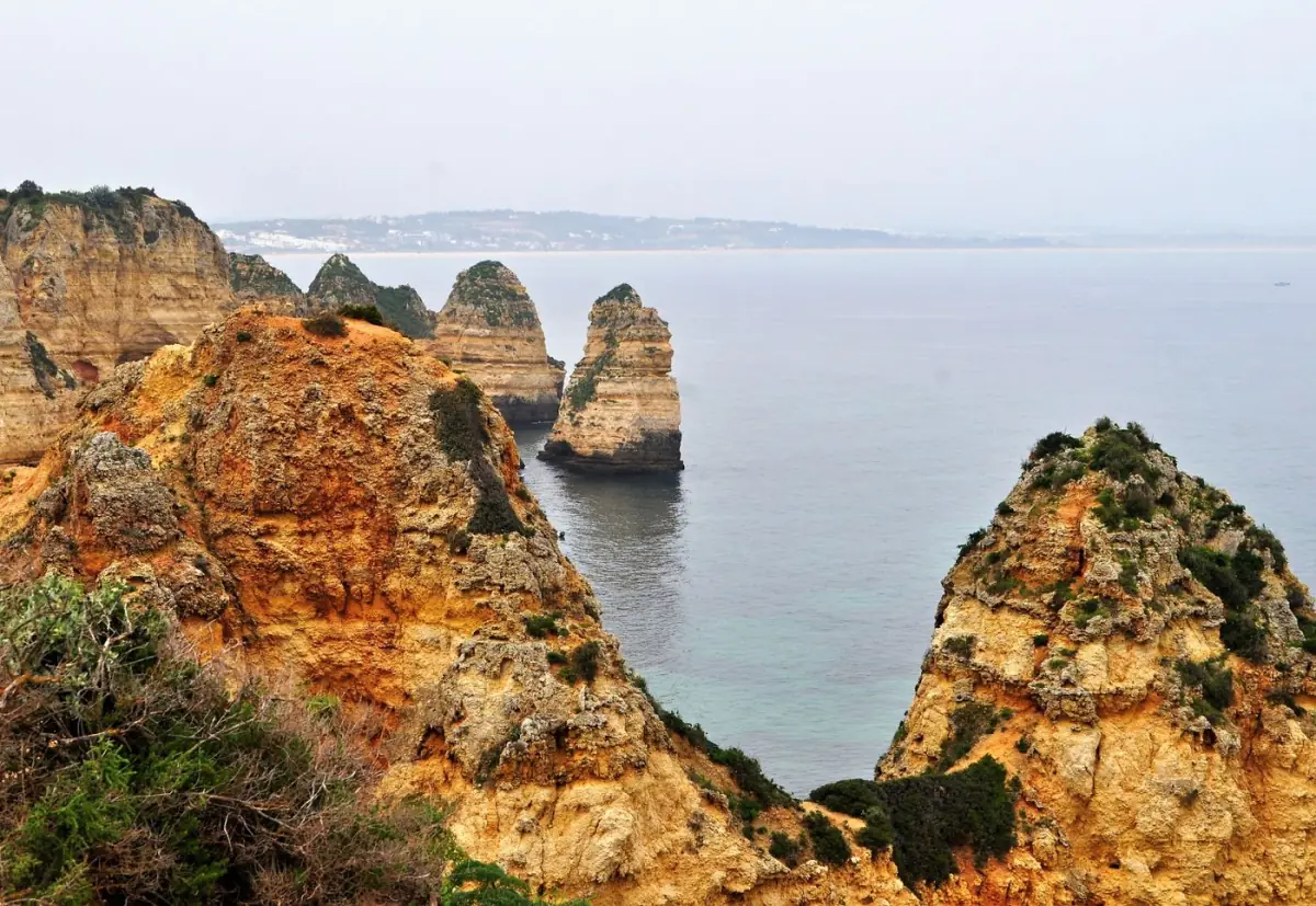 Falésias costeiras ocres a pique sobre o mar azul no Barlavento algarvio