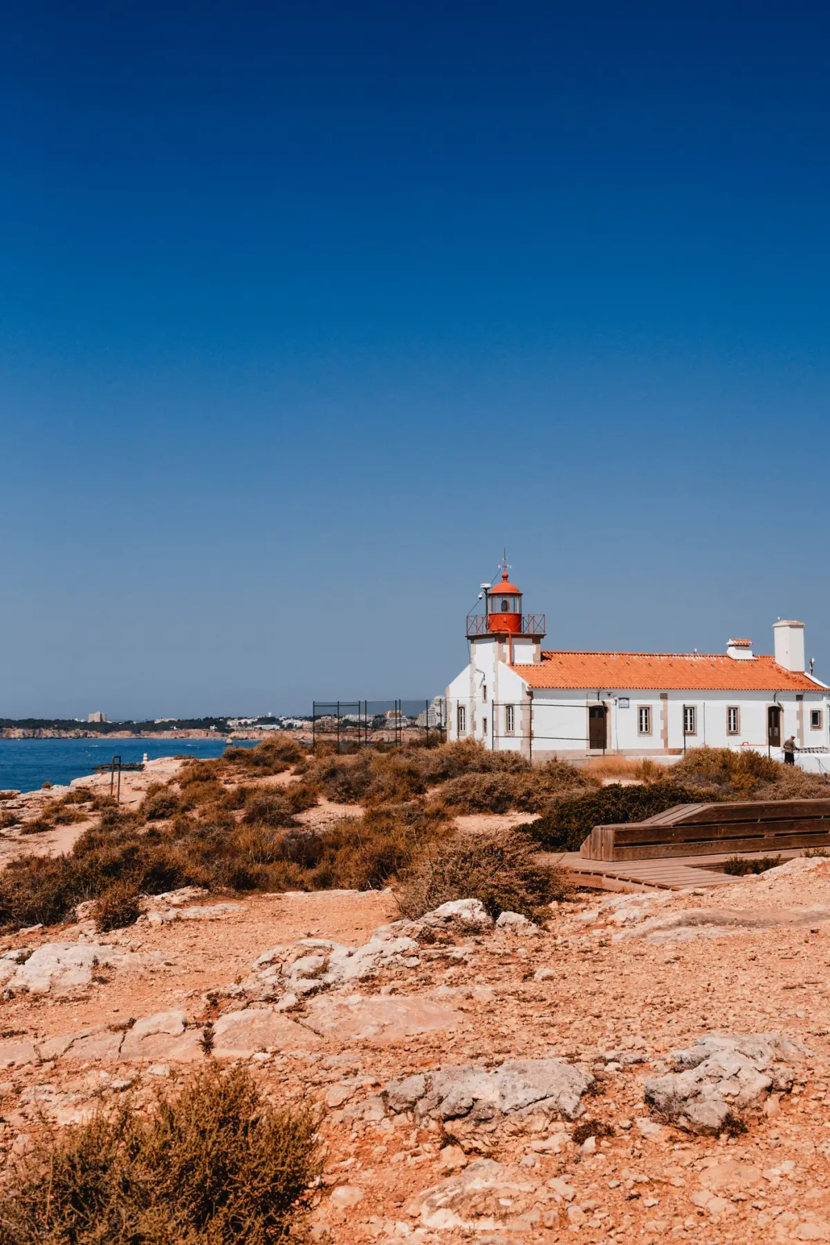 Farol numa costa rochosa do Algarve ao fim do dia, perto de Alvor