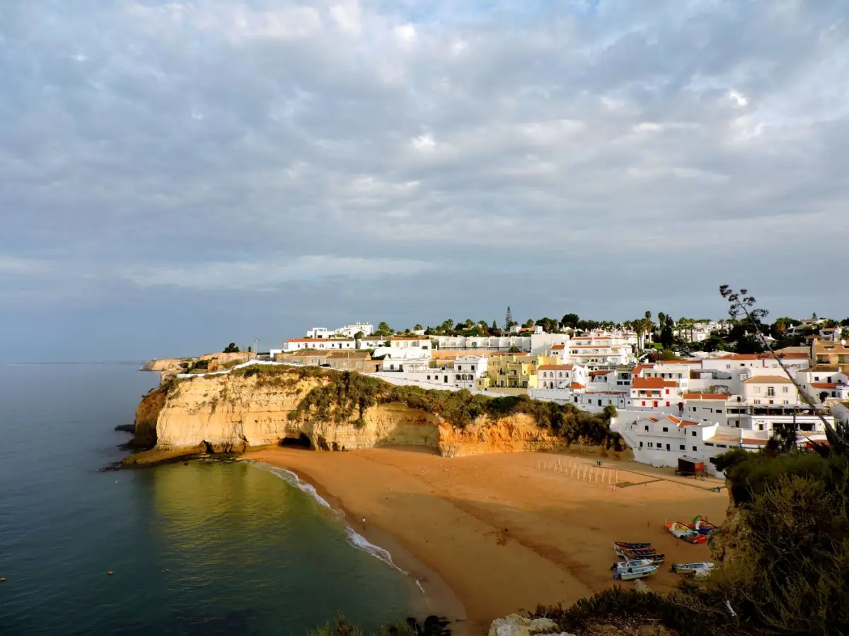 Aldeia costeira de casas brancas sobre falésia dourada junto à praia em Armação de Pêra