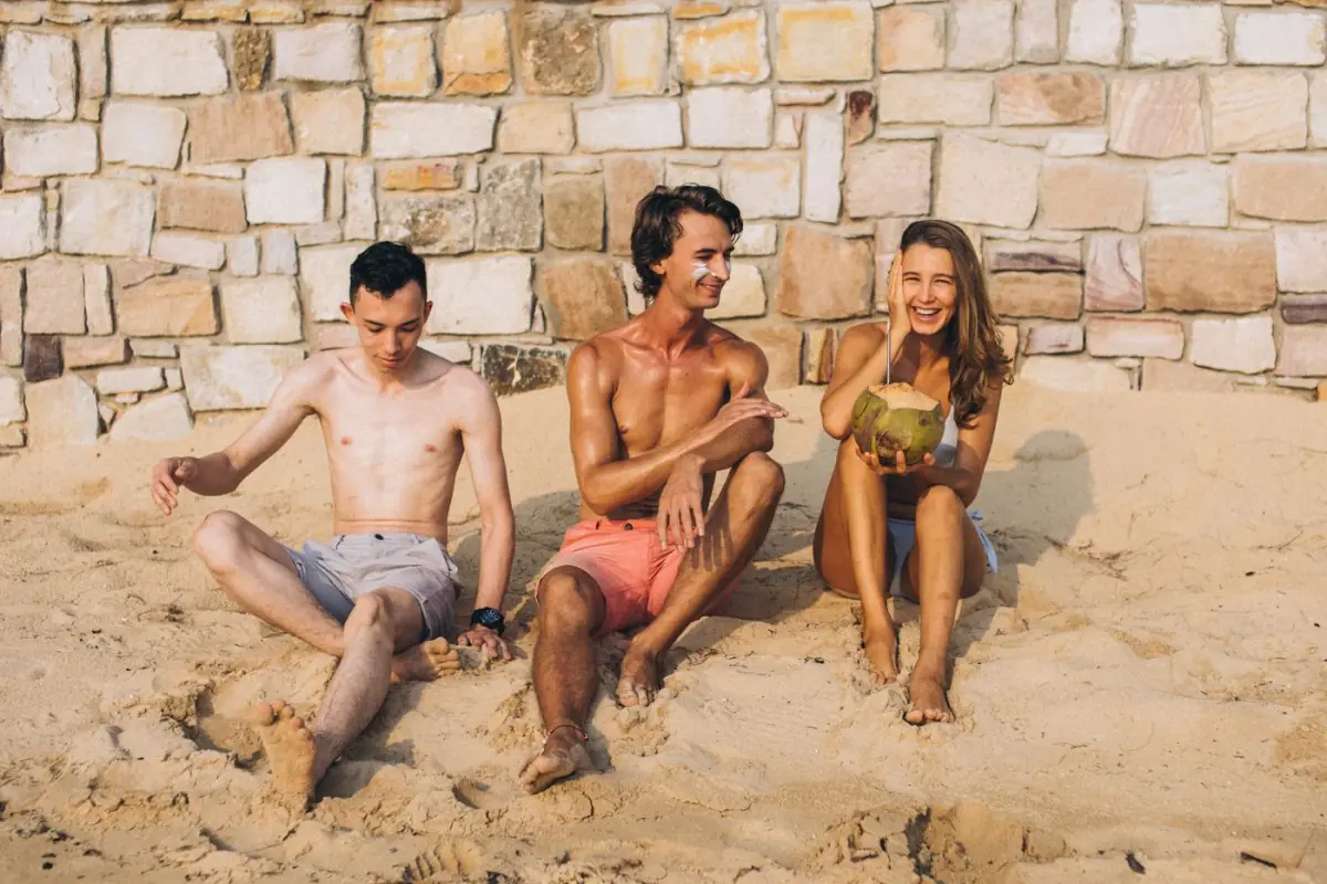 Amigos a relaxar com bebidas numa praia do Algarve junto às falésias