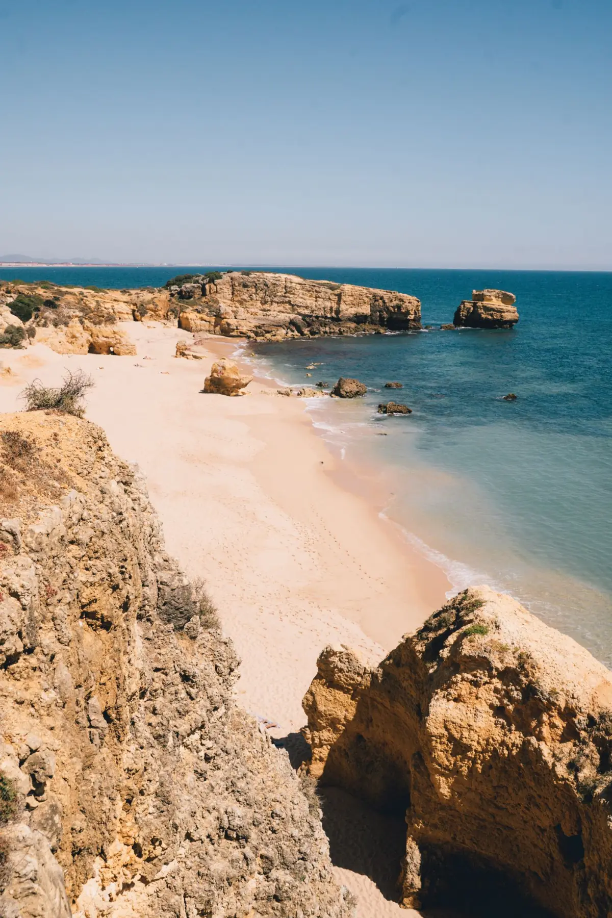 Costa rochosa e falésias da Praia da Marinha num dia de céu limpo