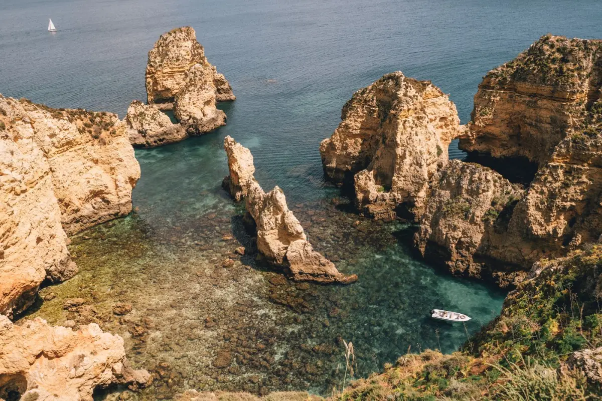 Pináculos de rocha sobre água turquesa na costa de Lagos