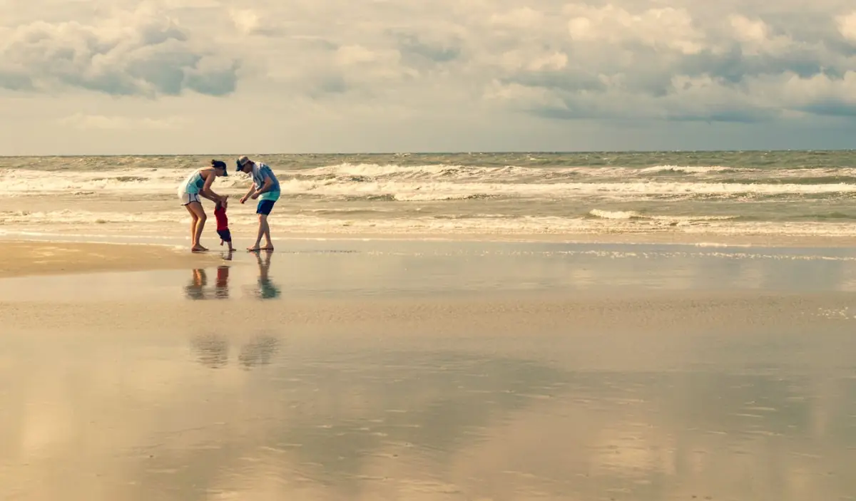 Família a brincar na água pouco profunda junto a uma praia calma do Algarve