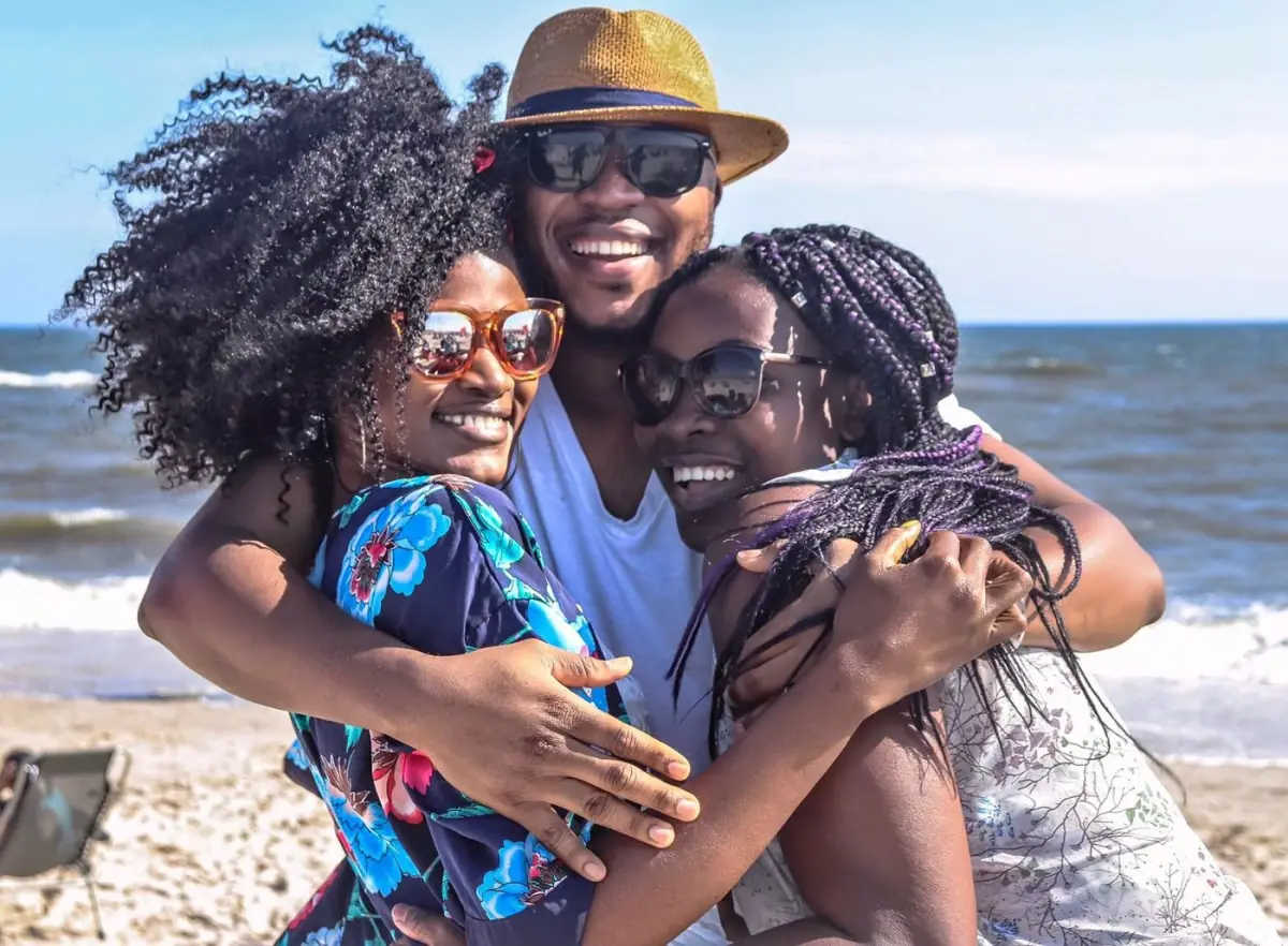 Três amigos num abraço descontraído numa praia do Algarve ao final do dia