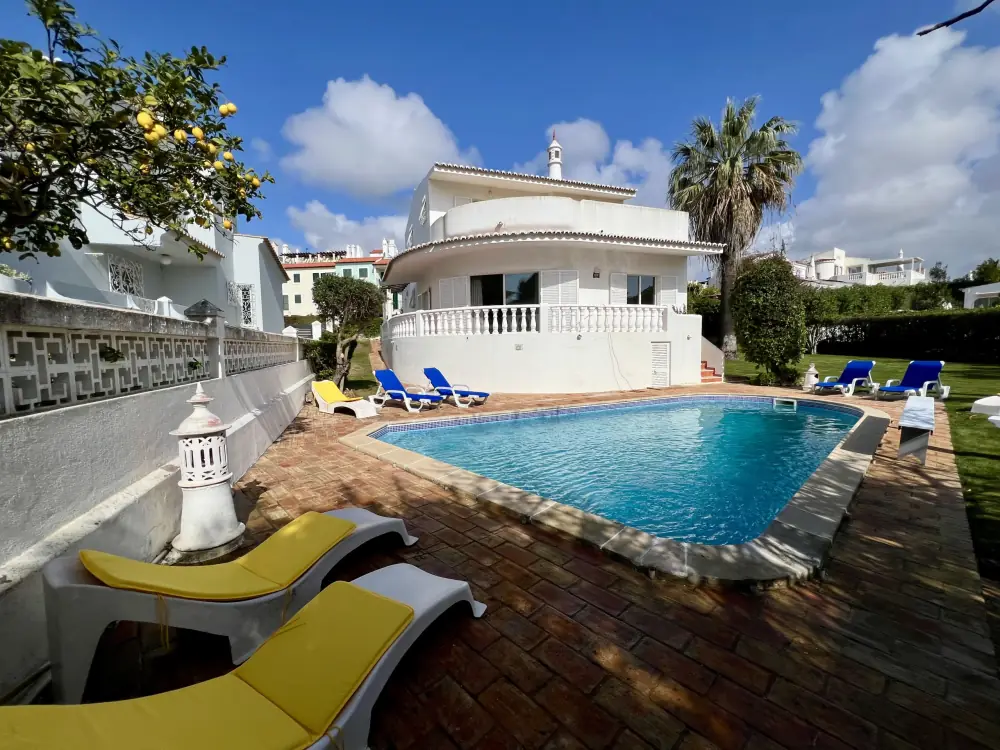 White villa with a pool, sun loungers and a lemon tree in a walled garden in Vilamoura